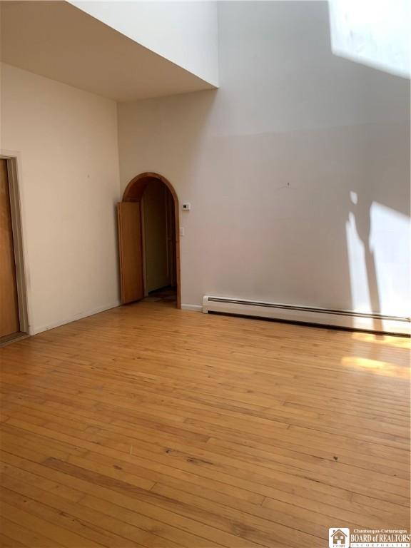 749-753 W Main, Ellington, NY 14732 - spare room featuring light wood finished floors, arched walkways, and a baseboard radiator