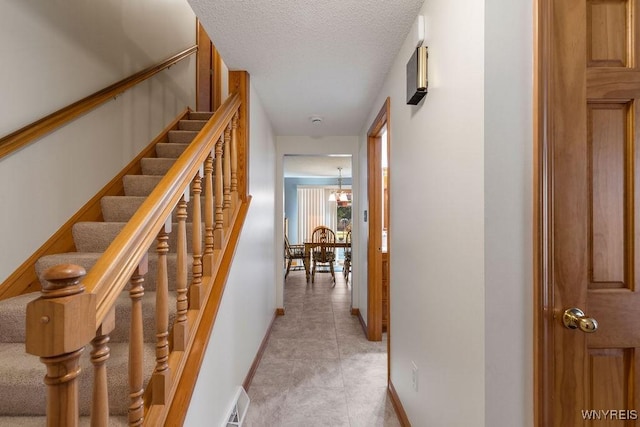 86 Hitching Post Ln, Amherst, NY 14228 - hall with light tile patterned floors, a chandelier, a textured ceiling, and stairway