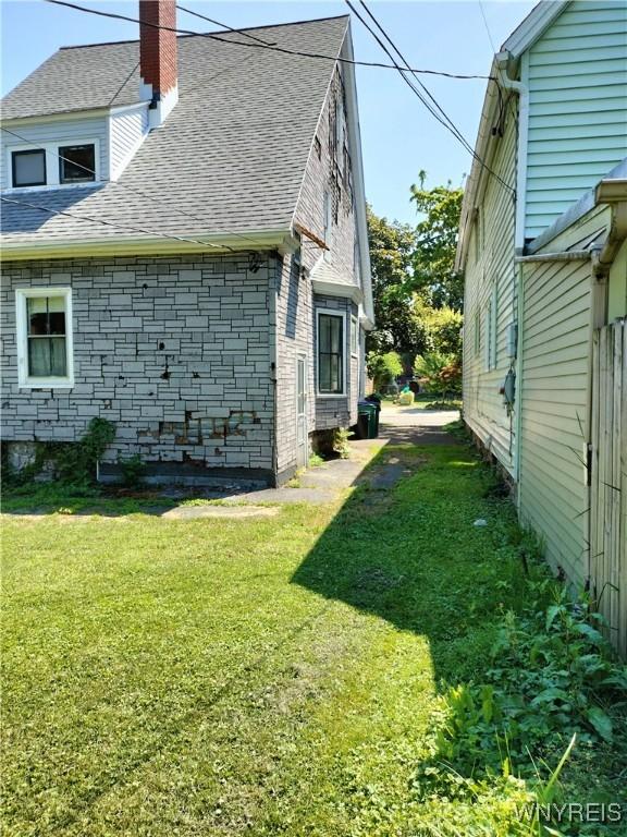 20 Chenango St, Buffalo, NY 14213 - view of home's exterior with a shingled roof, a chimney, a lawn, and brick siding
