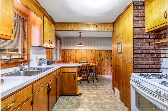 473 Seneca Creek Rd, West Seneca, NY 14224 - kitchen featuring white gas stove, light countertops, wood walls, stone finish flooring, and brown cabinets