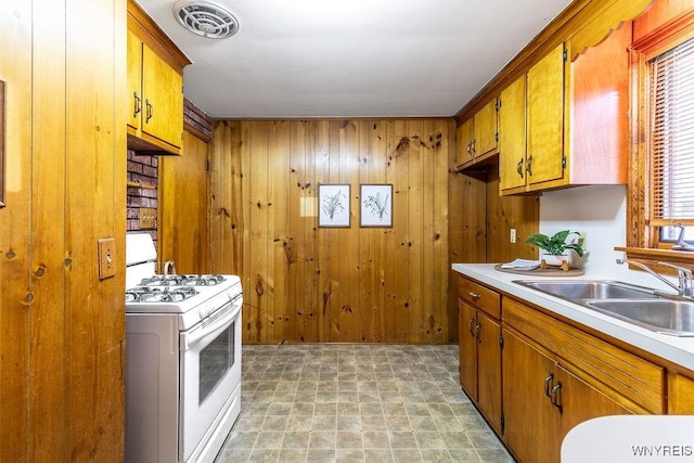 473 Seneca Creek Rd, West Seneca, NY 14224 - kitchen with white range with gas stovetop, wooden walls, light countertops, and brown cabinets
