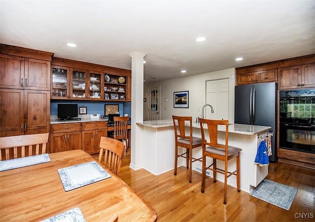 101 Luan Cir, Dewitt, NY 13078 - kitchen with light wood-style floors, a kitchen breakfast bar, a peninsula, recessed lighting, and glass insert cabinets
