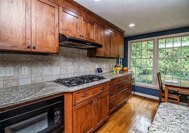 101 Luan Cir, Dewitt, NY 13078 - kitchen with under cabinet range hood, black appliances, light wood-style floors, light stone countertops, and backsplash