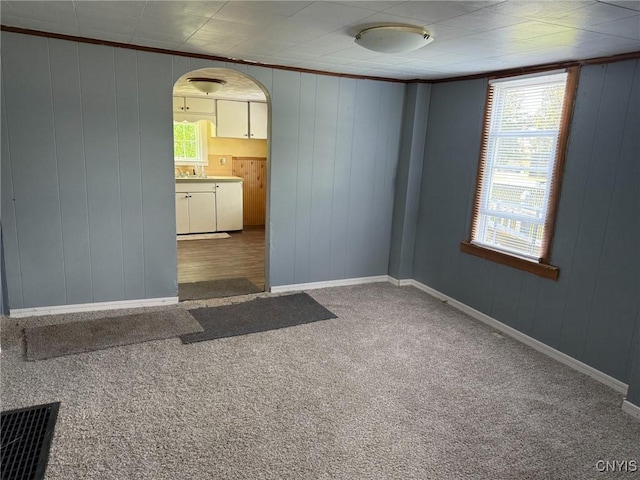 231 N Main St, Oneida, NY 13421 - unfurnished room featuring arched walkways, healthy amount of natural light, carpet flooring, wooden walls, and crown molding