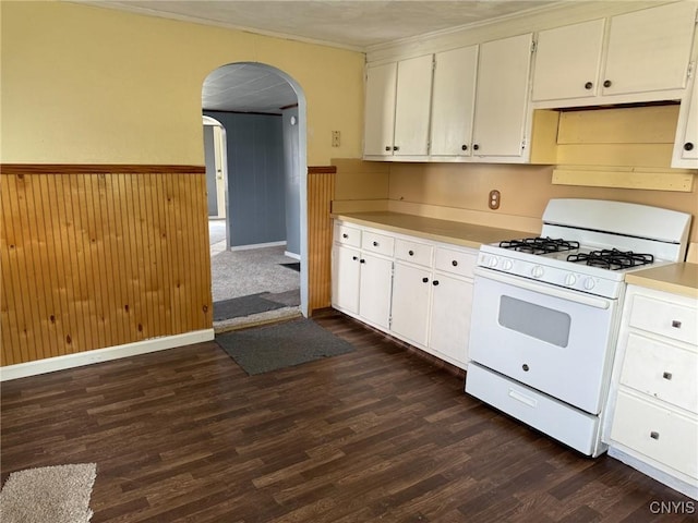 231 N Main St, Oneida, NY 13421 - kitchen featuring white gas stove, arched walkways, a wainscoted wall, dark wood-style floors, and white cabinets