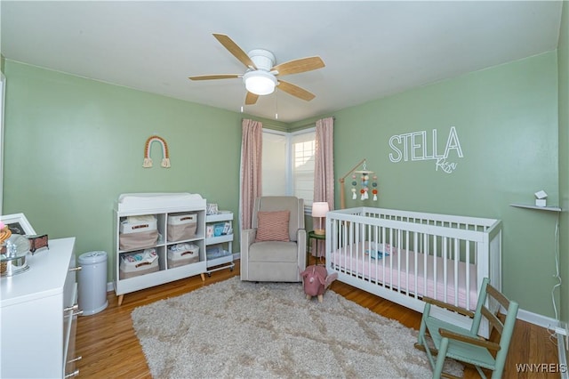 282 N Wrexham Ct, Tonawanda, NY 14150 - bedroom with a crib, wood finished floors, and a ceiling fan