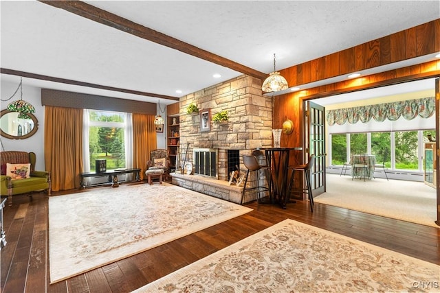 5 Hingham Rd, Utica, NY 13501 - living area with beamed ceiling, wood-type flooring, wooden walls, a baseboard radiator, and a stone fireplace