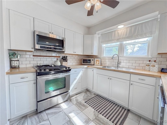 8 Harnden St, Auburn, NY 13021 - kitchen featuring stainless steel appliances, ceiling fan, white cabinets, and tasteful backsplash
