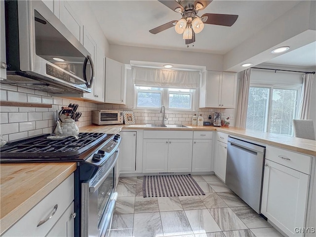 8 Harnden St, Auburn, NY 13021 - kitchen with stainless steel appliances, healthy amount of natural light, backsplash, white cabinetry, and recessed lighting