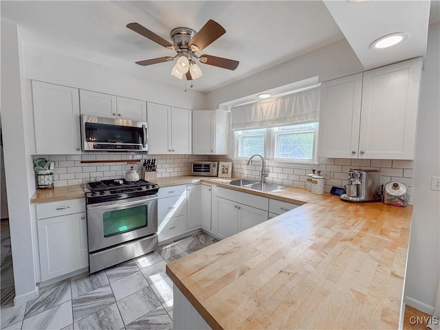 8 Harnden St, Auburn, NY 13021 - kitchen with stainless steel appliances, white cabinets, a peninsula, wood counters, and decorative backsplash