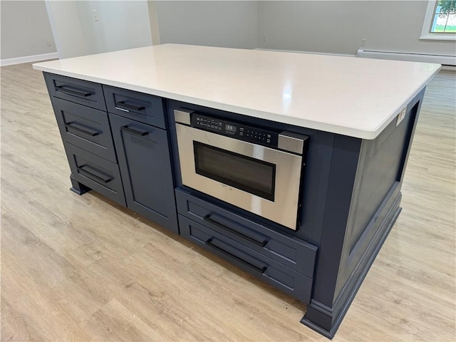6365 Honey Run Rd, Hornellsville, NY 14843 - kitchen with light wood-style flooring, stainless steel microwave, a baseboard heating unit, a center island, and light countertops