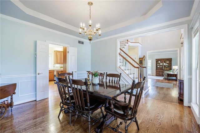 117 Neuchatel Ln, Perinton, NY 14450 - dining space featuring a chandelier, stairs, light wood-style flooring, a raised ceiling, and ornamental molding
