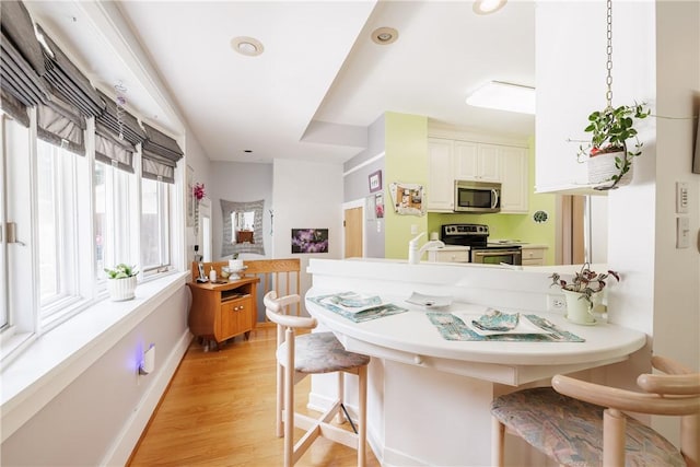125 Sunset Dr, Brighton, NY 14618 - kitchen featuring appliances with stainless steel finishes, a kitchen breakfast bar, a peninsula, light wood finished floors, and recessed lighting