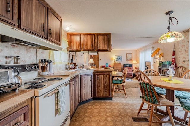 218 Campbell Rd, Gouverneur, NY 13642 - kitchen with white electric range oven, a peninsula, pendant lighting, under cabinet range hood, and light countertops