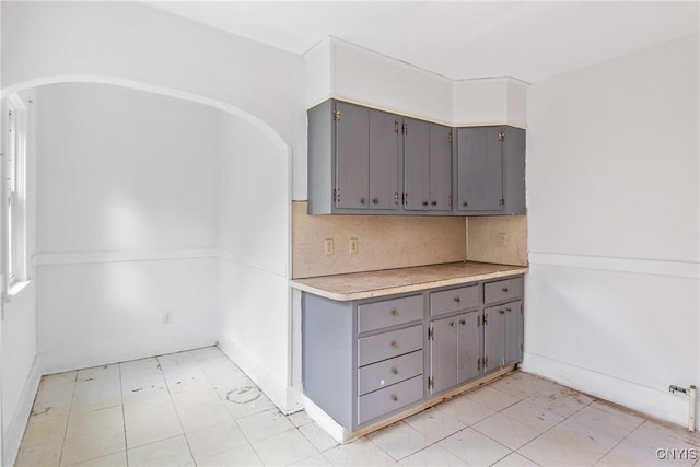 201 Mosley Dr, Syracuse, NY 13206 - kitchen with gray cabinetry, arched walkways, light countertops, and backsplash