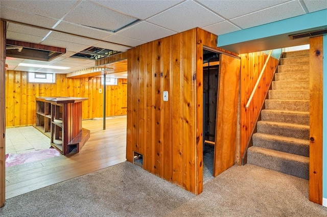 179 Down St, Henrietta, NY 14623 - basement with stairway, wooden walls, a drop ceiling, carpet floors, and a bar