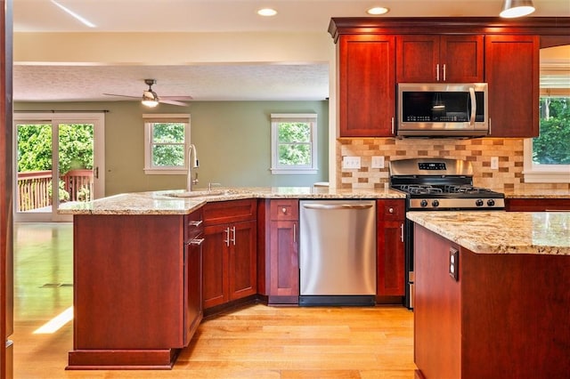 179 Down St, Henrietta, NY 14623 - kitchen with appliances with stainless steel finishes, light wood-style floors, dark brown cabinets, tasteful backsplash, and light stone counters