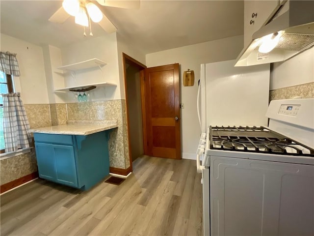 2 Washington St, North Dansville, NY 14437 - kitchen featuring gas range gas stove, under cabinet range hood, blue cabinets, open shelves, and light wood-style flooring