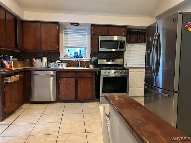 38 Hines St, Buffalo, NY 14220 - kitchen featuring stainless steel appliances, backsplash, dark brown cabinets, light tile patterned floors, and dark countertops