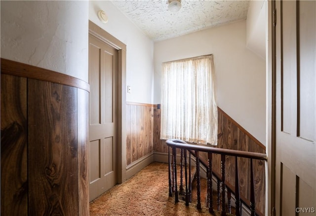 103 Stanwix St, Rome, NY 13440 - hallway featuring a wainscoted wall, an upstairs landing, carpet flooring, a textured ceiling, and wood walls