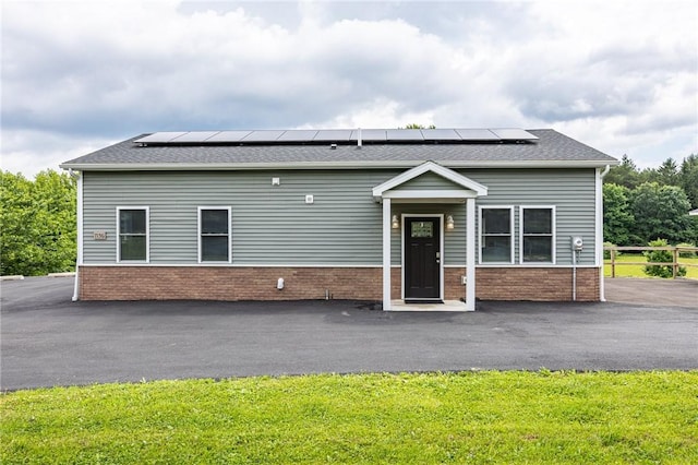 7156 County Line Rd, Naples, NY 14512 - view of front of property featuring roof mounted solar panels, roof with shingles, a front yard, and brick siding