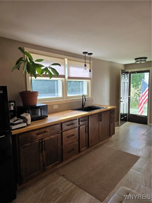 4049 River Rd, Lewiston, NY 14174 - kitchen with black appliances, butcher block countertops, hanging light fixtures, and dark brown cabinets