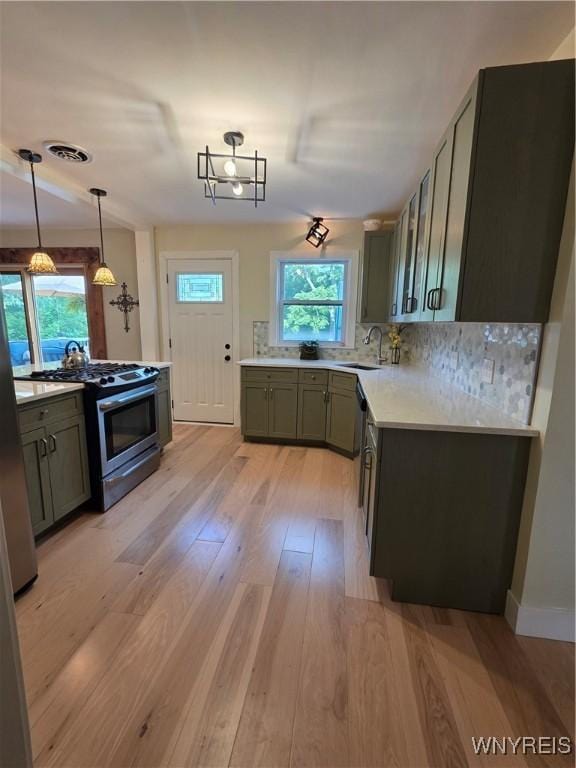 4049 River Rd, Lewiston, NY 14174 - kitchen featuring stainless steel appliances, light wood-style flooring, light countertops, tasteful backsplash, and pendant lighting