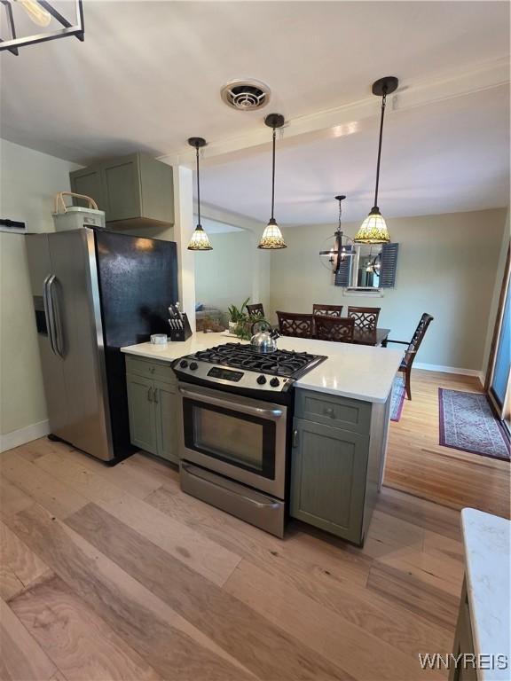 4049 River Rd, Lewiston, NY 14174 - kitchen with appliances with stainless steel finishes, light countertops, light wood finished floors, and decorative light fixtures