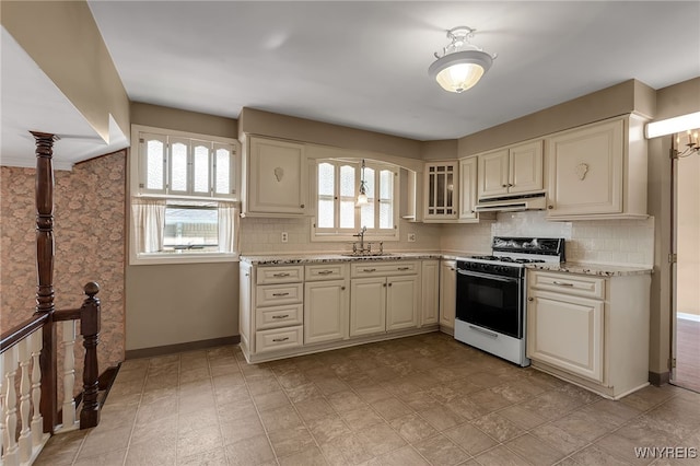 17 Frantzen Ter, Cheektowaga, NY 14227 - kitchen with white range with gas stovetop, under cabinet range hood, decorative backsplash, and light stone countertops