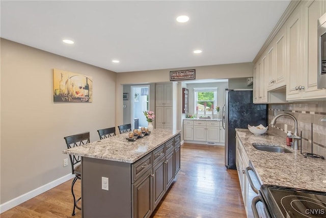 4956 Crestwood Ln, Onondaga, NY 13215 - kitchen featuring a kitchen breakfast bar, decorative backsplash, light stone countertops, light wood-style floors, and appliances with stainless steel finishes