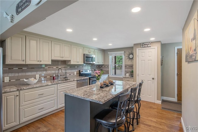 4956 Crestwood Ln, Onondaga, NY 13215 - kitchen with appliances with stainless steel finishes, backsplash, recessed lighting, a breakfast bar area, and light wood-type flooring