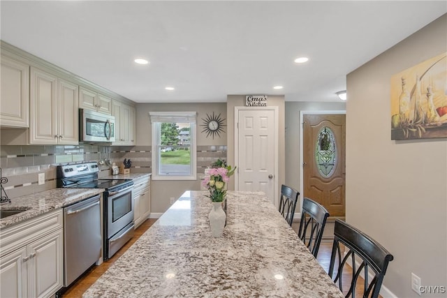 4956 Crestwood Ln, Onondaga, NY 13215 - kitchen with stainless steel appliances, light stone counters, decorative backsplash, recessed lighting, and wood finished floors