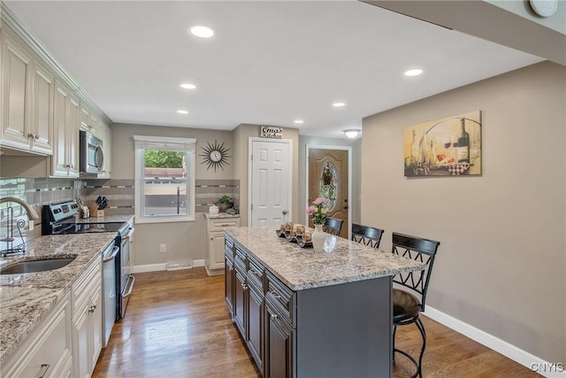 4956 Crestwood Ln, Onondaga, NY 13215 - kitchen featuring appliances with stainless steel finishes, a breakfast bar area, decorative backsplash, light stone counters, and recessed lighting