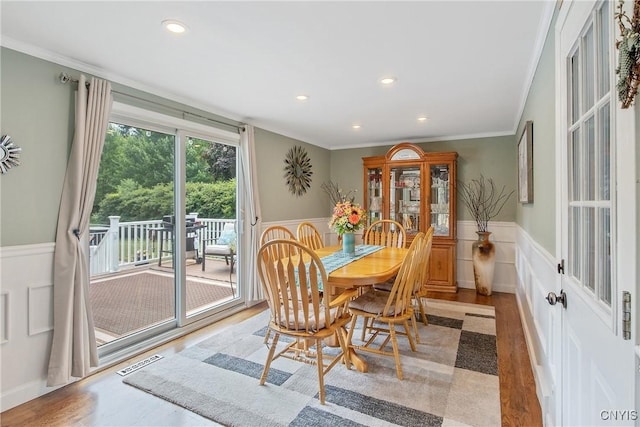 4956 Crestwood Ln, Onondaga, NY 13215 - dining space featuring a wainscoted wall, wood finished floors, crown molding, recessed lighting, and a decorative wall