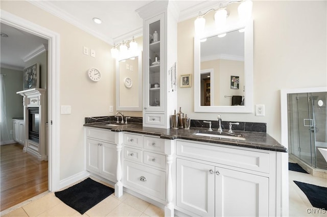 8067 Irish Mist Ln, Manlius, NY 13104 - bathroom with ornamental molding, double vanity, a glass covered fireplace, tile patterned flooring, and a shower stall