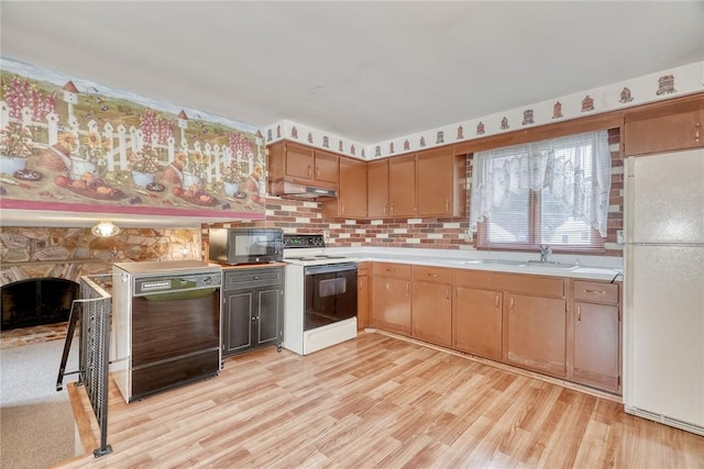 163 Auramar Dr, Irondequoit, NY 14609 - kitchen with black appliances, under cabinet range hood, light countertops, light wood-style flooring, and a stone fireplace