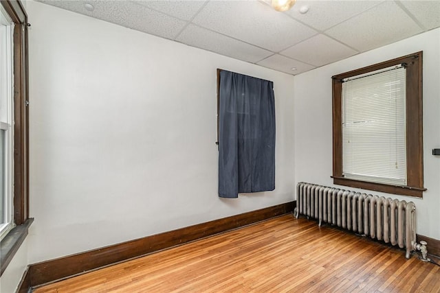 1570 Mount Hope Ave, Rochester, NY 14620 - spare room featuring radiator heating unit, a drop ceiling, and hardwood / wood-style floors