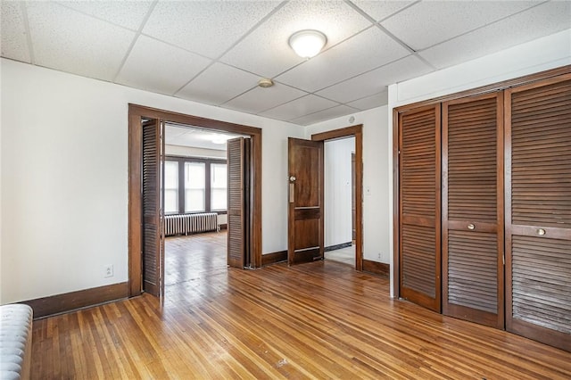 1570 Mount Hope Ave, Rochester, NY 14620 - unfurnished bedroom with radiator heating unit, a drop ceiling, a closet, and light wood finished floors