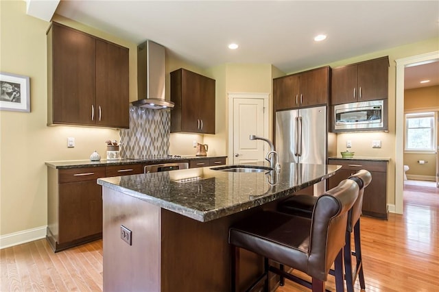 1537 Cranberry Pond, Victor, NY 14564 - kitchen featuring wall chimney range hood, appliances with stainless steel finishes, a breakfast bar area, light wood-style flooring, and dark stone countertops
