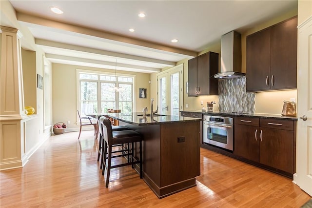 1537 Cranberry Pond, Victor, NY 14564 - kitchen featuring oven, wall chimney exhaust hood, a breakfast bar, tasteful backsplash, and light wood finished floors