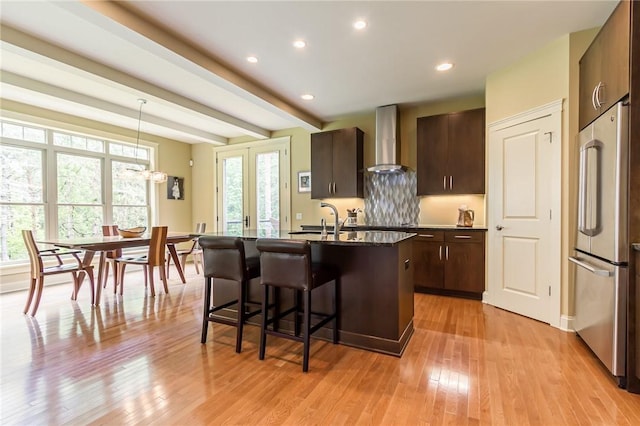 1537 Cranberry Pond, Victor, NY 14564 - kitchen with wall chimney range hood, stainless steel fridge, an island with sink, a kitchen breakfast bar, and dark brown cabinetry
