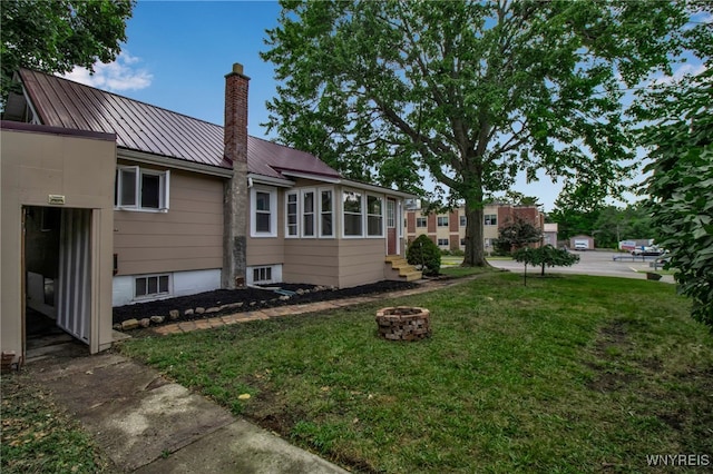 201 Ohio St, Ridgeway, NY 14103 - view of side of property featuring a yard, a chimney, a standing seam roof, an outdoor fire pit, and a metal roof