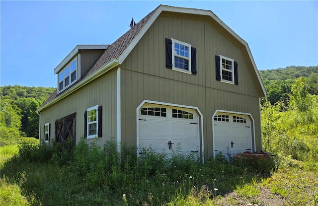 4197 County Highway 26, Colchester, NY 13782 - view of side of property with a detached garage, roof with shingles, and a forest view
