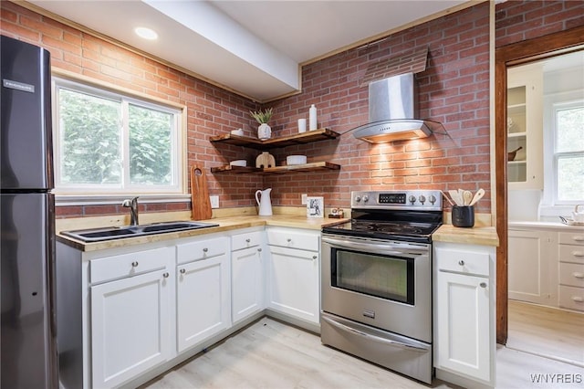 72 Manchester St, Rochester, NY 14621 - kitchen featuring appliances with stainless steel finishes, light countertops, white cabinetry, wall chimney exhaust hood, and light wood-style floors