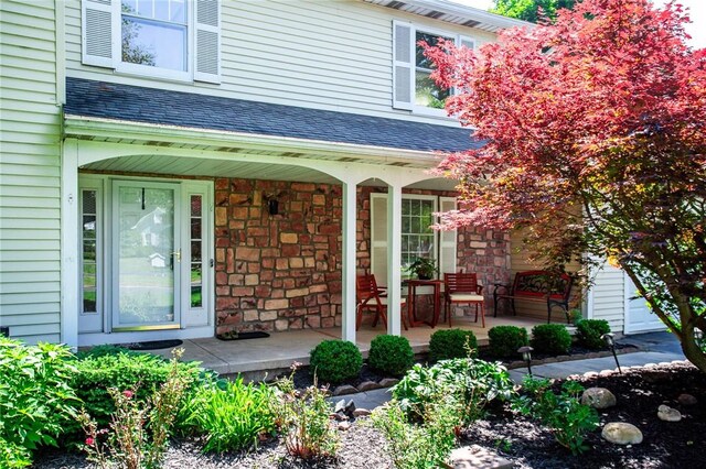 47 Stonington Dr, Pittsford, NY 14534 - view of exterior entry with covered porch, stone siding, and a shingled roof