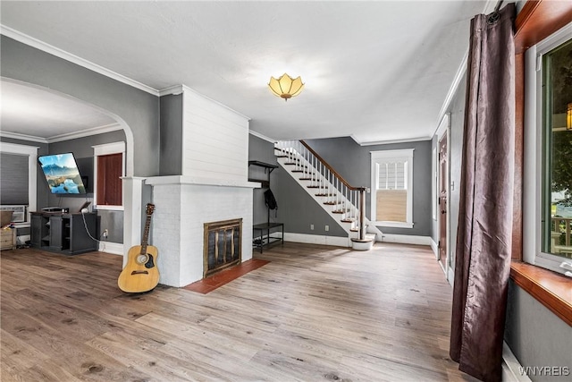39 Colonial Ave, Lancaster, NY 14086 - unfurnished living room featuring wood finished floors, a fireplace, crown molding, stairway, and arched walkways
