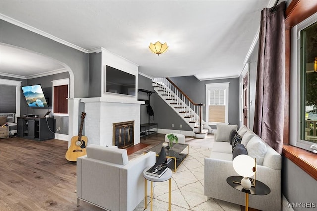 39 Colonial Ave, Lancaster, NY 14086 - living room featuring crown molding, arched walkways, wood finished floors, a brick fireplace, and stairs