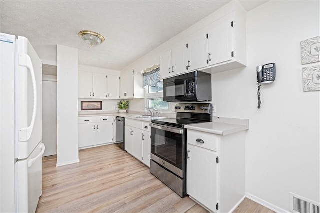 975 Whitlock Rd, Irondequoit, NY 14609 - kitchen with stainless steel range with electric stovetop, freestanding refrigerator, black microwave, dishwasher, and light wood-style floors