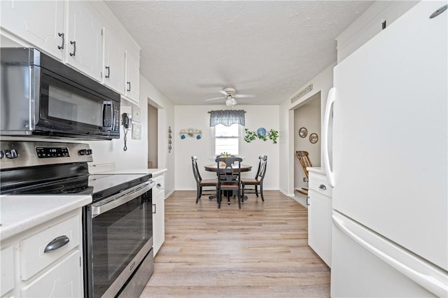 975 Whitlock Rd, Irondequoit, NY 14609 - kitchen featuring freestanding refrigerator, electric stove, black microwave, light wood-style flooring, and white cabinets