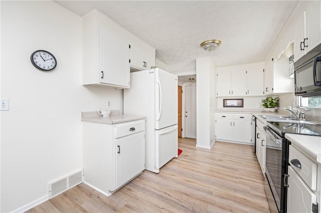 975 Whitlock Rd, Irondequoit, NY 14609 - kitchen featuring stainless steel electric range, freestanding refrigerator, light wood-style floors, white cabinetry, and a textured ceiling